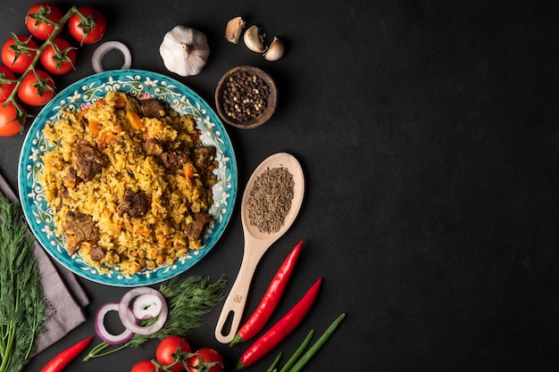 Pilaf fragrante con carne e verdure vista dall'alto su un piatto su sfondo nero con spazio copia