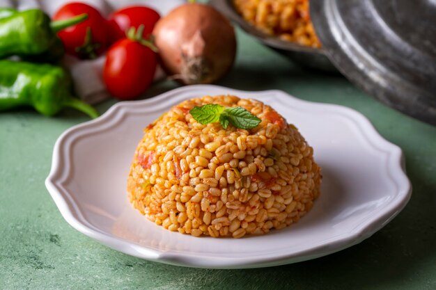 Pilaf turco tradizionale di bulgur con salsa di pomodoro nel piatto (nome turco; meyhane pilavi)