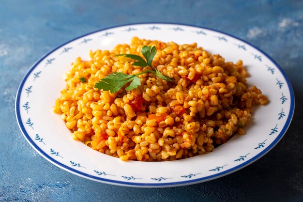 Pilaf turco tradizionale di bulgur con salsa di pomodoro nel piatto (nome turco; meyhane pilavi)