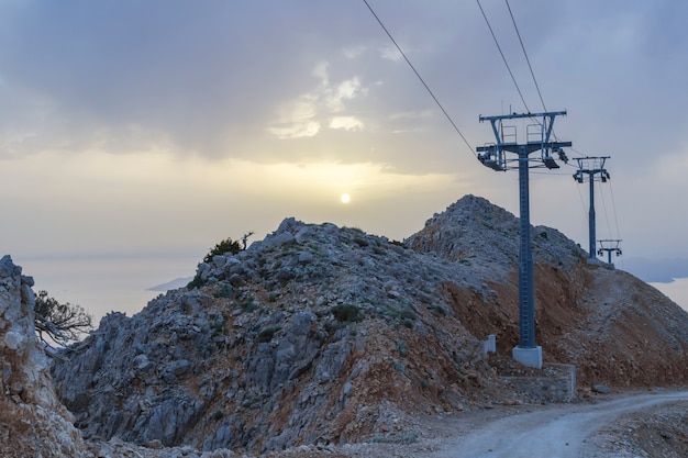 Pilastri metallici della seggiovia. Pendii di montagna in estate. Lontano baia del mare.