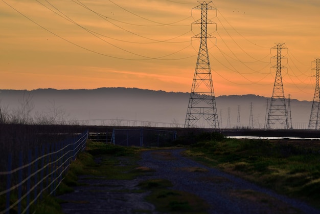 Pilastro elettrico sul campo contro il cielo durante il tramonto