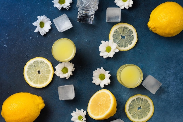 Pile di limoncello fresco con limoni e fiori su sfondo blu