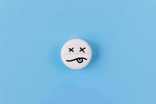 Pillola con un'emoji morta su sfondo blu Il concetto di sovradosaggio di droga