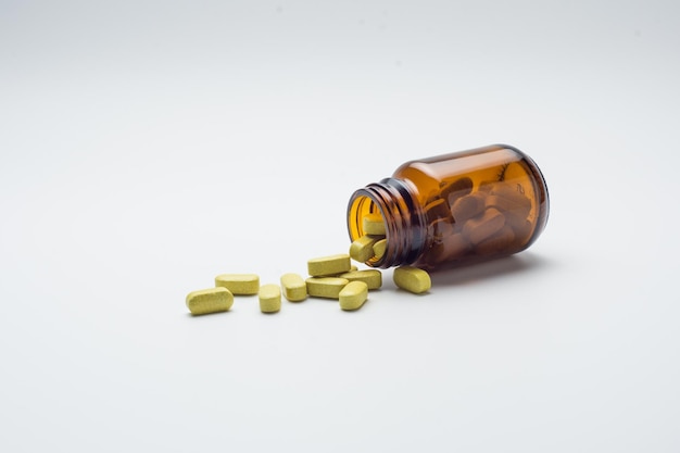 pillola di compresse di erbe gialle verdastre e bottiglia di vetro marrone, medicina tradizionale, pillole organiche