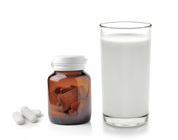 Pillola e bicchiere di latte isolati su fondo bianco