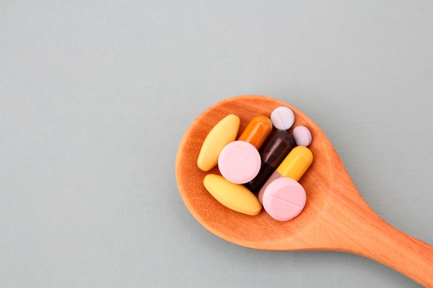Pillole assortite, compresse e capsule della medicina farmaceutica sul cucchiaio di legno.