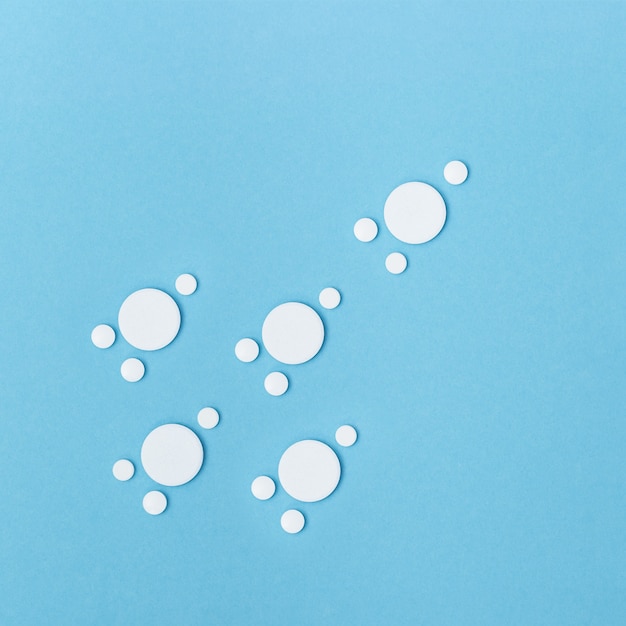 Pillole bianche a forma di molecola, virus o batteri sulla superficie blu