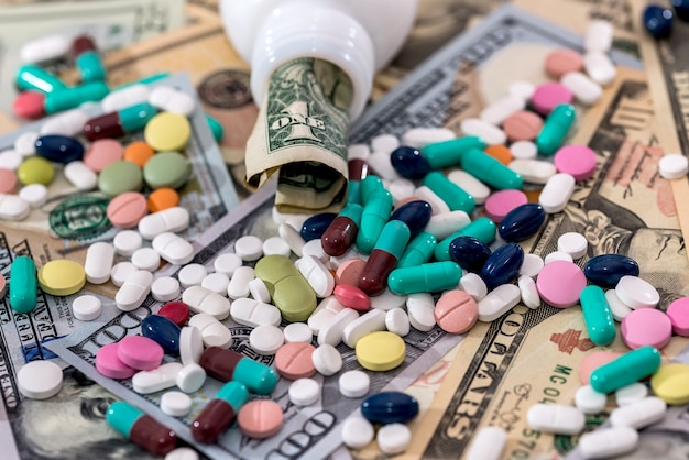 Pillole colorate con banconote in dollari da vicino