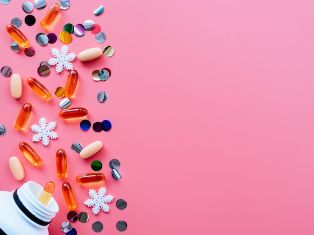 Pillole, coriandoli, giocattoli di Natale su uno sfondo rosa