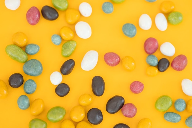 Pillole di caramelle al cioccolato colorate isolate su sfondo giallo