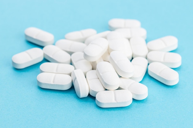 Pillole di medicina bianche su sfondo blu Sfondo di farmacia