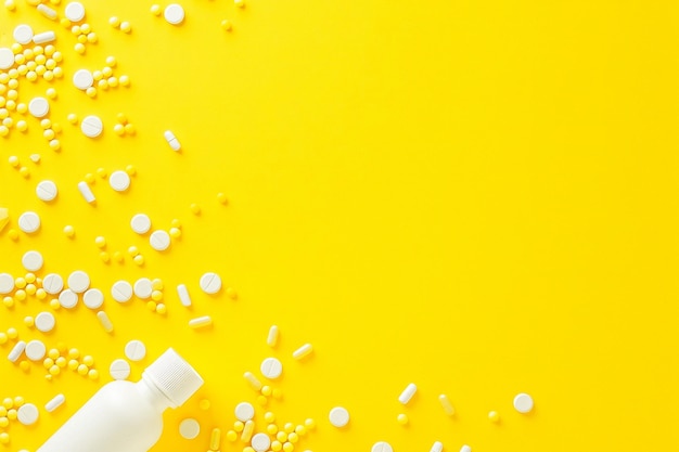 Pillole di medicina bianche versate da una bottiglia di pillole di plastica su uno sfondo giallo medicina creativa