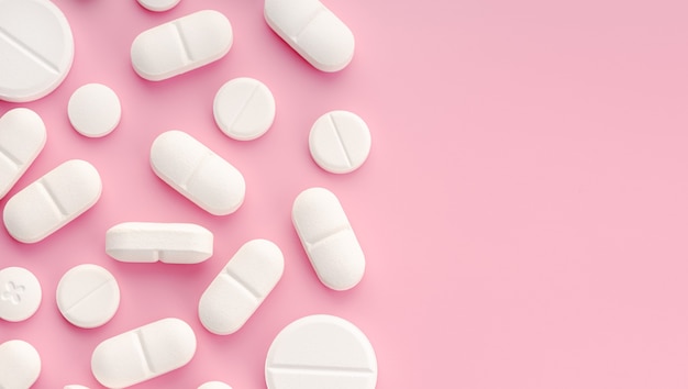 Pillole di medicina su sfondo rosa. Copia spazio. Vista dall'alto