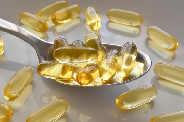 Pillole di olio o olio di enotera o capsule di integratori di omega 3 o olio di pesce sul cucchiaio