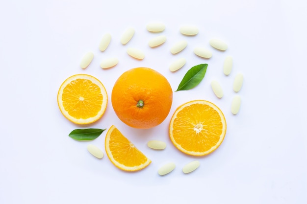 Pillole di vitamina C con frutta arancione su bianco.