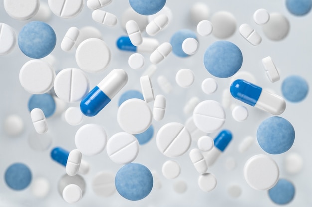 Pillole e capsule galleggianti bianche e blu. Background medico
