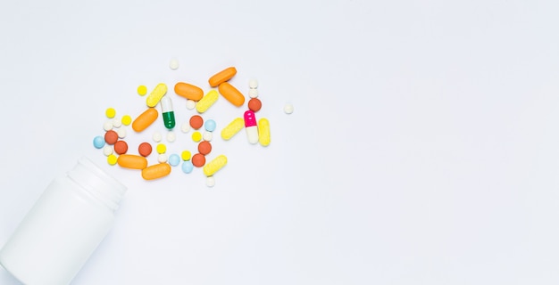 Pillole e flaconi di pillole su sfondo bianco Bottiglia di pillole versata isolata
