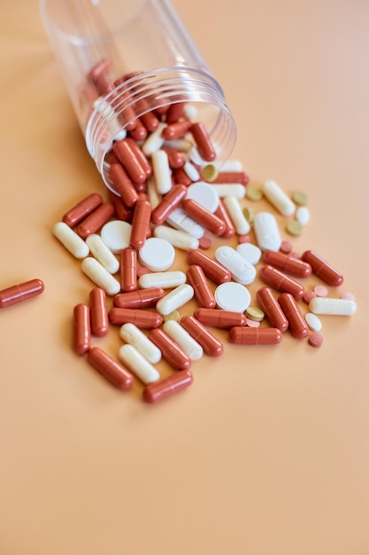 Pillole mediche colorate diverse piatte con bottiglia su sfondo arancione