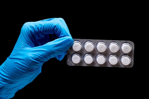 Pillole mediche in blister su sfondo nero isolato con riflesso in mano