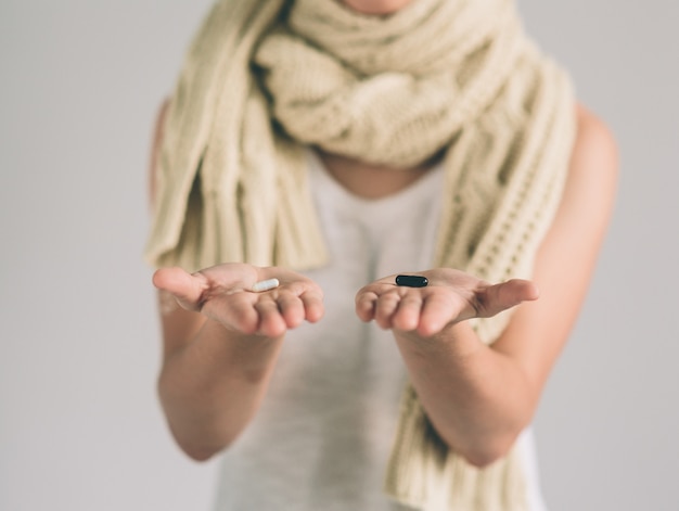 Pillole nelle mani di una donna su fondo bianco