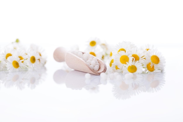 pillole omeopatiche con fiori primaverili su fondo di legno bianco