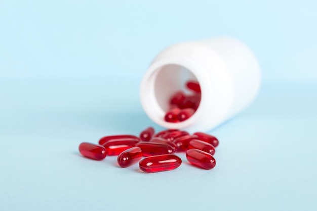 Pillole rosse versate intorno a un flacone di pillola Medicinali e pillole da prescrizione sfondo piatto Capsule mediche rosse