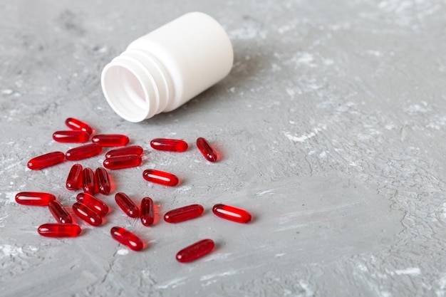 Pillole rosse versate intorno a un flacone di pillola Medicinali e pillole da prescrizione sfondo piatto Capsule mediche rosse