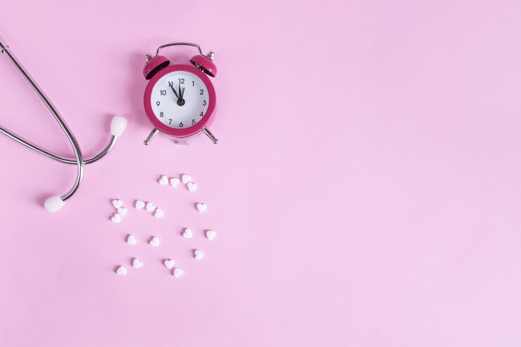 Pillole, stetoscopio e sveglia su un rosa con spazio di copia. Medico è tempo di prendere la medicina.