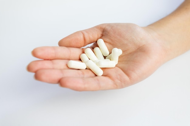 Pillole tenute in mano su uno sfondo bianco integrazione e dosaggio del farmaco per la salute salute mentale e fisica del paziente