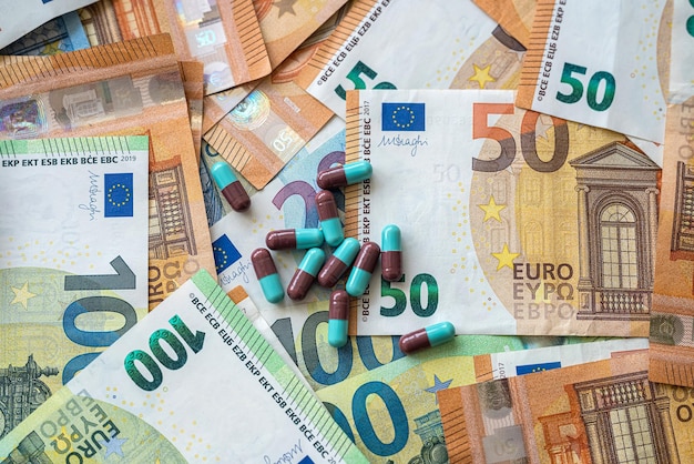 Pillole verdi giacciono su una pila di banconote in euro costo costoso di sfondo dell'assistenza sanitaria