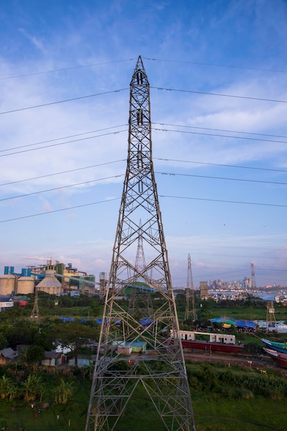 Pilone di elettricità ad alta tensione con sfondo paesaggio urbano e cielo blu