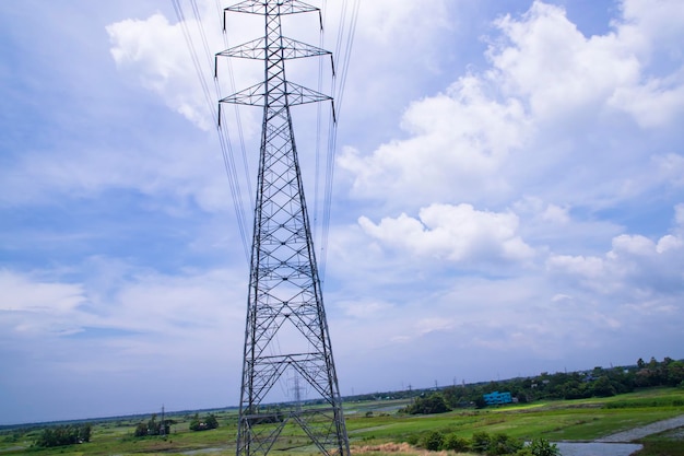 Pilone di elettricità ad alta tensione sotto il cielo blu nuvoloso