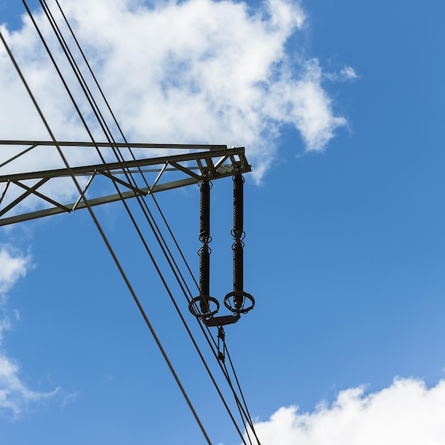 Pilone di elettricità sull'alta tensione dell'industria del cielo nuvoloso blu