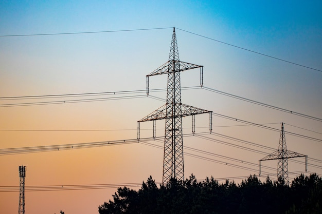 Pilone e linea elettrica di trasmissione nel tramonto.