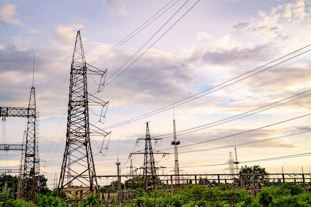 Piloni dell'elettricità contro il tramonto arancione e giallo. Messa a fuoco selettiva.