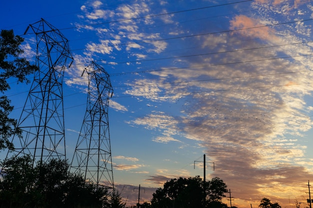 Piloni di potenza ad alta tensione nel cavo elettrico del sole del cielo del tramonto della scena del tramonto