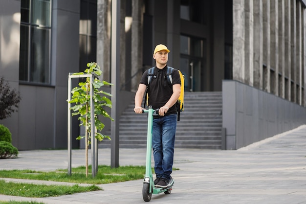 Pilota che consegna pasti con scooter elettrico in città Concetto ecologico di cibo a consegna rapida