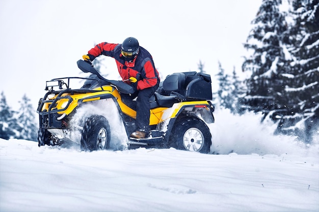 Pilota che guida nella gara di quad in inverno nella foresta