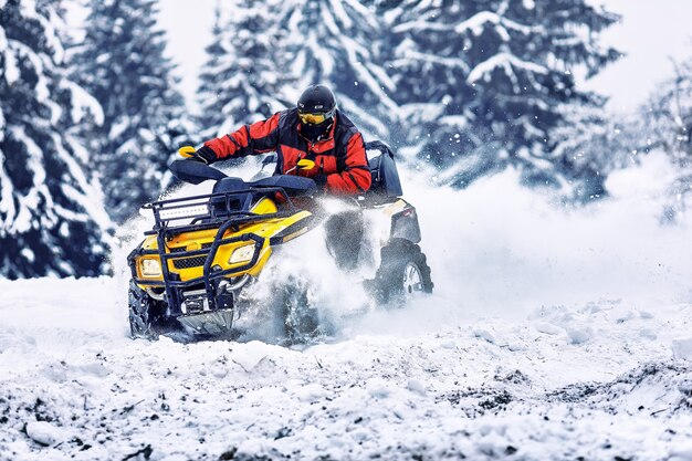 Pilota che guida nella gara di quad in inverno nella foresta