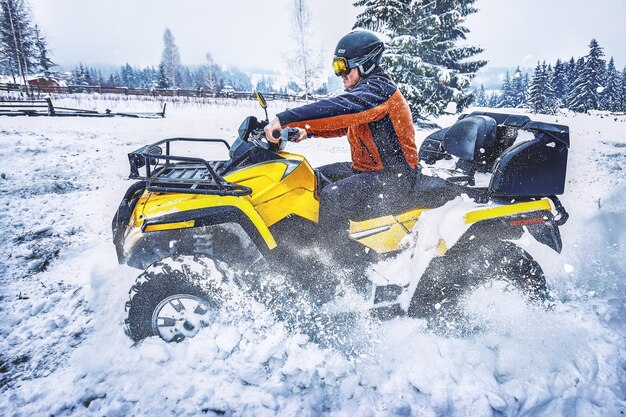 Pilota che guida nella gara di quad in inverno nella foresta