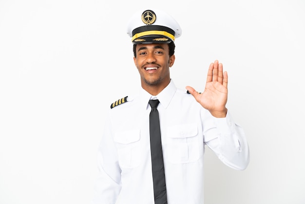 Pilota di aeroplano afroamericano sopra fondo bianco isolato che saluta con la mano con l'espressione felice
