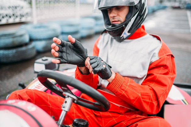 Pilota di go-kart nel casco sulla pista di velocità di kart. Gara di kart