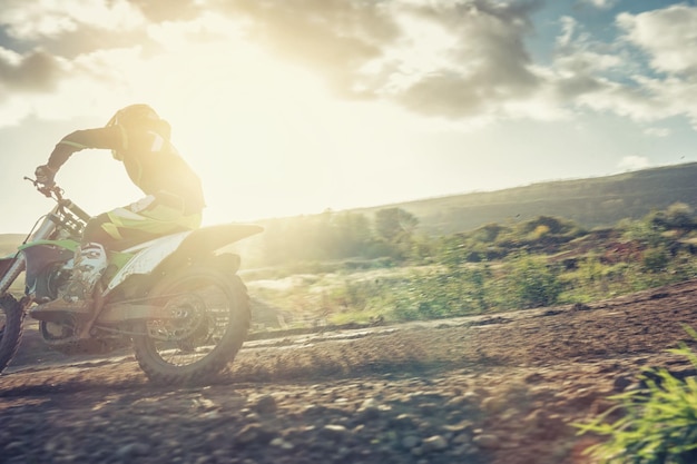 Pilota di Motocross MX in curva durante il tramonto su una pista sterrata