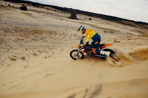 Pilota di motocross professionista che scivola giù per la collina di sabbia