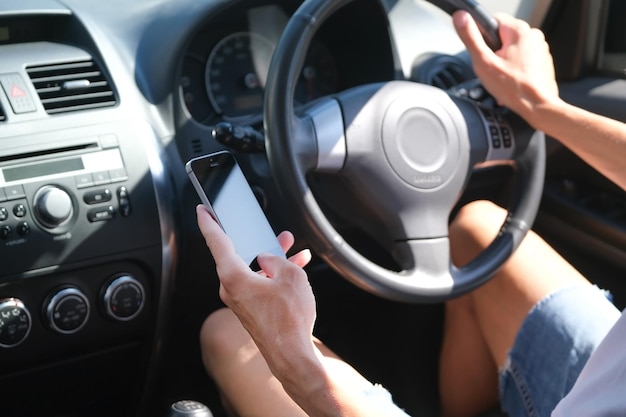 pilota maschio al volante guardando il telefono in mano