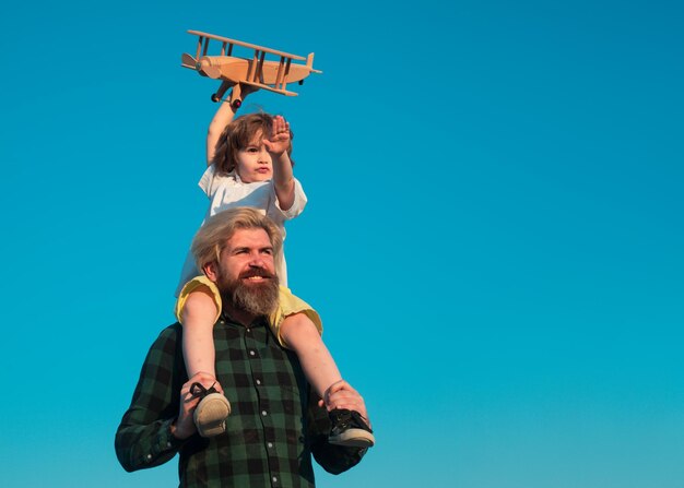 Pilota ragazzo bambino. Padre e figlio che giocano con l'aeroplano di legno.