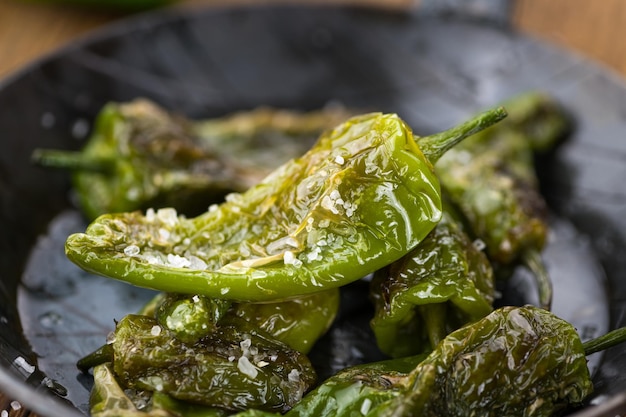 Pimientos de Padron sul fuoco selettivo del fondo di legno