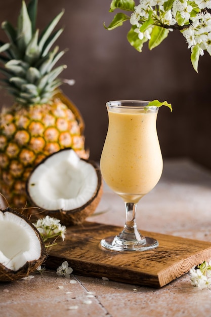 Pina colada cocktail di ananas o Lassi su un tavolo in legno rustico