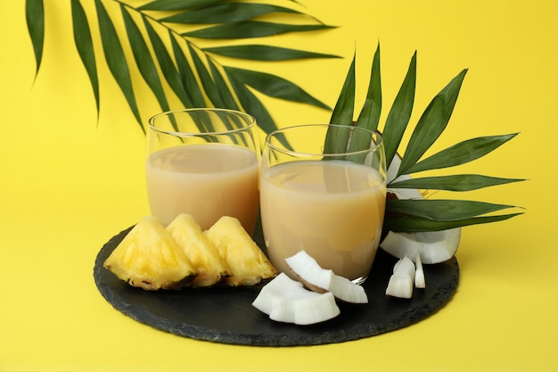 Pina colada cocktail e ingredienti su sfondo giallo.