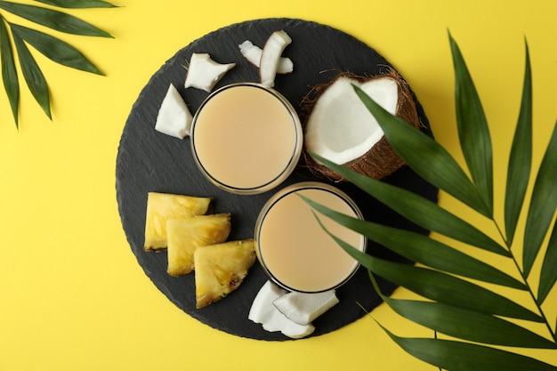 Pina colada cocktail e ingredienti su sfondo giallo.